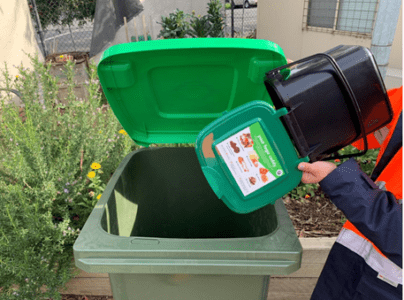 Person in Hi-Vis vest emities compost bin into council garden organics bin